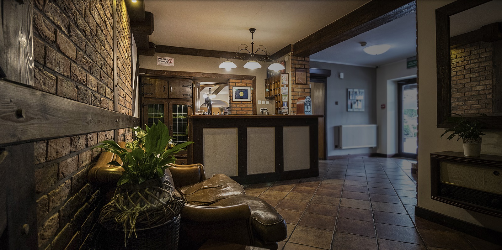 Recepcja Zajazdu Harasówka — ceglane wnętrze z drewnianymi akcentami